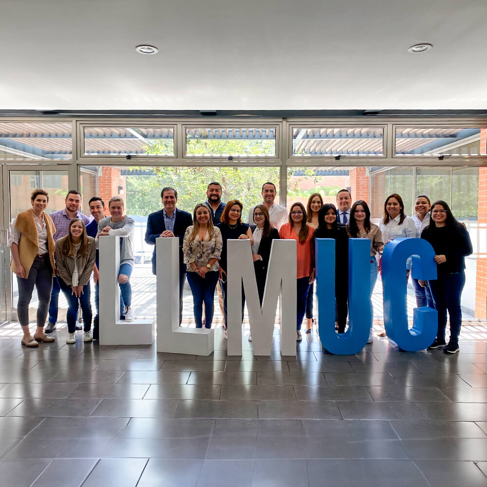 Un grupo de hombres y mujeres junto a unas letras de plástico que dicen LLM UC