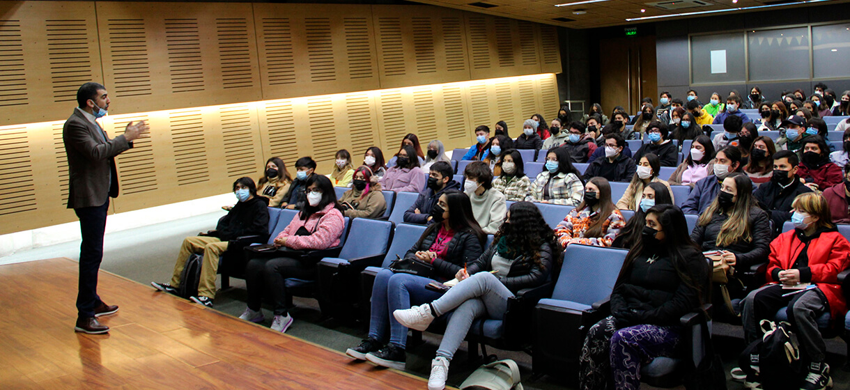 Un hombre en un escenario hablándole a un grupo de personas sentadas en un auditorio